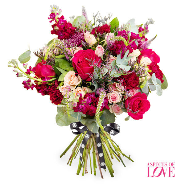 vibrant cerise pink roses, captivating purple stocks, and graceful pink spray roses