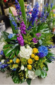 Blue, purple, white, yellow and green funeral flowers